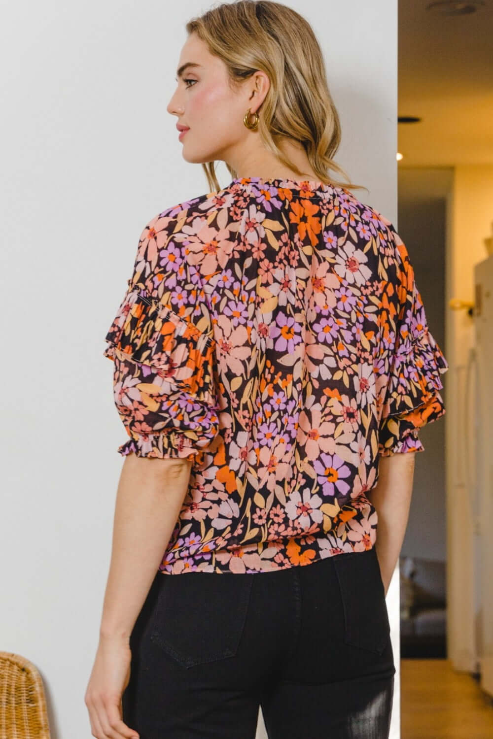 Woman wearing Floral Tie Neck Ruffled Blouse with colorful floral print and ruffled details from the back.