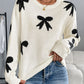 Quirky bow graphic round neck long sleeve sweater in white with black bows, perfect for playful and cozy style.