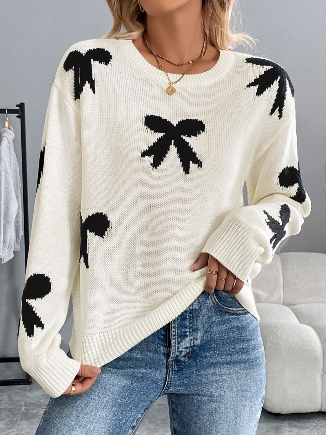 Quirky bow graphic round neck long sleeve sweater in white with black bows, perfect for playful and cozy style.