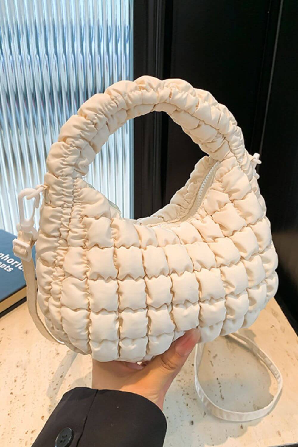 Quilted puffy crossbody bag with removable strap, elegant design in creamy white, perfect for versatile fashion styles.