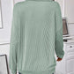 Back view of woman wearing light green ribbed knit sweater with long sleeves.