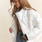 Woman wearing a chic white quilted mock neck puffer jacket with diamond stitch detail, perfect for stylish warmth and comfort.