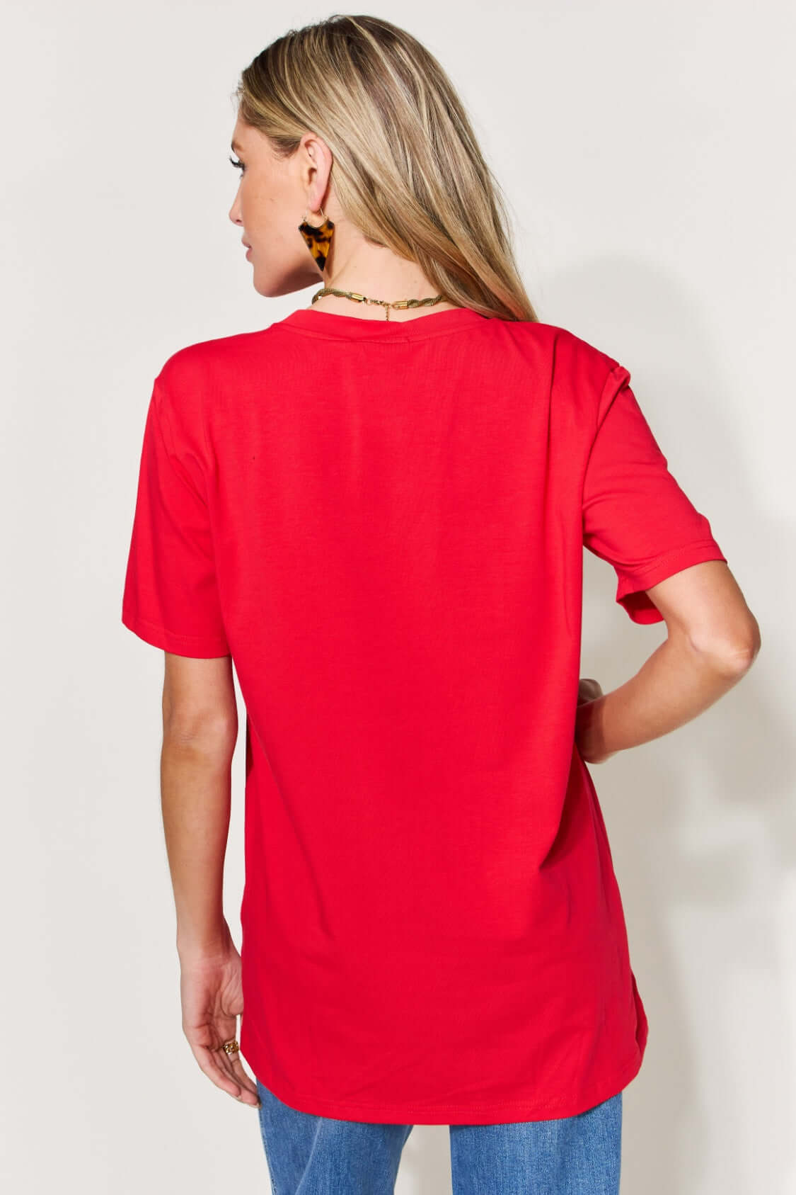 Woman wearing a red MAMA Round Neck Short Sleeve T-Shirt, shown from the back, paired with blue jeans.