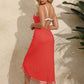 Woman wearing red backless tassel surplice spaghetti strap cover-up dress, standing outdoors near a wall with plants.