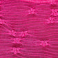 Close-up of pink semi-sheer fabric with a textured pattern and floral accents