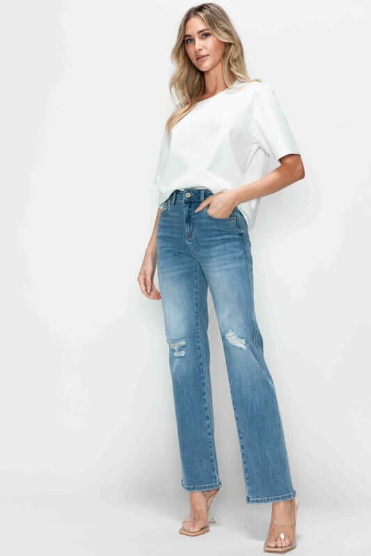 Stylish model in bytos distressed high rise straight jeans paired with a white top and chic heels, showcasing modern elegance.