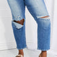 Emily High Rise Relaxed Jeans with ripped knee details, cropped length, styled casually with metallic sandals. Risen Jeans style.