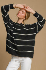 Woman wearing a cozy black and white striped round neck sweater, styled casually against a neutral background.