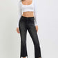 Trendy woman in RISEN full size raw hem cropped flare jeans paired with a stylish crop top and heels.