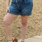 Woman modeling Maya Mid Rise Asymmetrical Shorts by Risen Jeans for a stylish and comfortable look