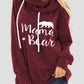 Woman wearing a maroon drawstring hoodie with "Mama Bear" graphic and bear silhouette.