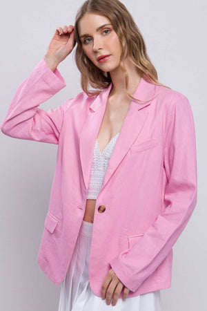 Woman wearing a pink one-button long sleeve linen blazer with a timeless and polished look, perfect for layering in transitional seasons.