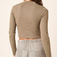 Back view of a woman wearing a ribbed mock neck long sleeve crop knit top paired with stylish patterned pants.