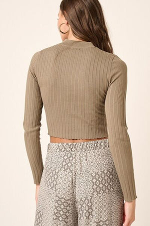 Back view of a woman wearing a ribbed mock neck long sleeve crop knit top paired with stylish patterned pants.