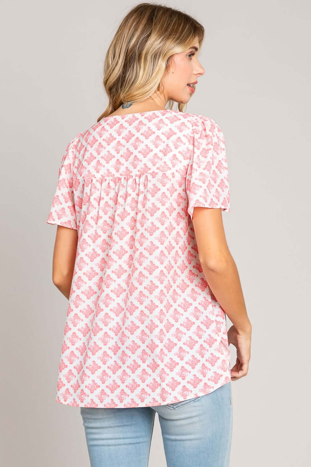 Back view of a woman wearing a pink and white Slit Printed V-Neck Flutter Sleeve Blouse with a charming printed design and graceful flutter sleeves