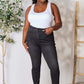 Woman wearing tummy control high waist denim jeans by Judy Blue Jeans, showcasing a slim silhouette with a white tank top.