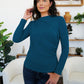 Model wearing FAM-FAM Ruched Mock Neck Long Sleeve T-Shirt in French Blue, showcasing stylish fall fashion in a cozy indoor setting.