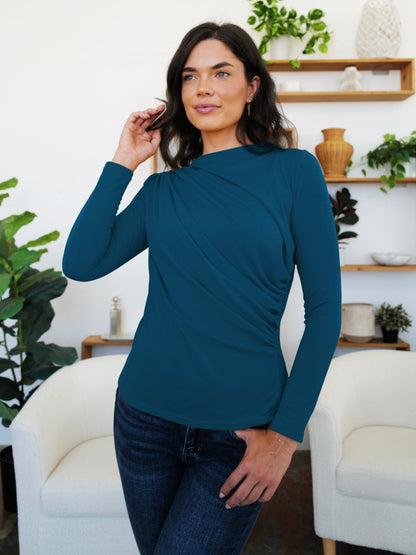 Model wearing FAM-FAM Ruched Mock Neck Long Sleeve T-Shirt in French Blue, showcasing stylish fall fashion in a cozy indoor setting.