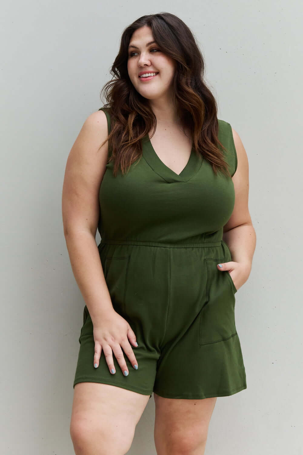 Woman wearing Forever Yours V-Neck Sleeveless Romper in Army Green, showcasing chic design and comfort for outdoor activities.