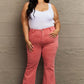 Curvy woman wearing Bailey High Waist Side Slit Flare Jeans in pink, paired with a white tank top, showcasing Risen Jeans' flattering fit.