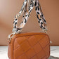 Stylish brown cassette woven crossbody bag with a chic leopard print strap on a marble surface.