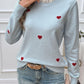 Woman wearing Devine Lace Detail Heart Long Sleeve Sweater with red heart accents and lace collar, paired with distressed jeans.