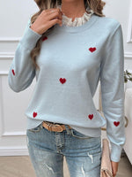 Woman wearing Devine Lace Detail Heart Long Sleeve Sweater with red heart accents and lace collar, paired with distressed jeans.