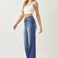 Trendy high waist raw hem wide leg jeans from Risen Jeans, perfect for a chic day-to-night look, modeled with a white crop top.