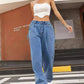 Fashionable woman in wide leg jeans with pockets and white corset top, standing outside.