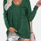 Woman wearing Bella Road round neck long sleeve green T-shirt with a pocket, paired with denim shorts and a beige handbag.