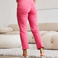 Woman wearing RFM Jeans Crop Dylan Full Size Tummy Control High Waist Raw Hem Jeans in pink standing indoors.