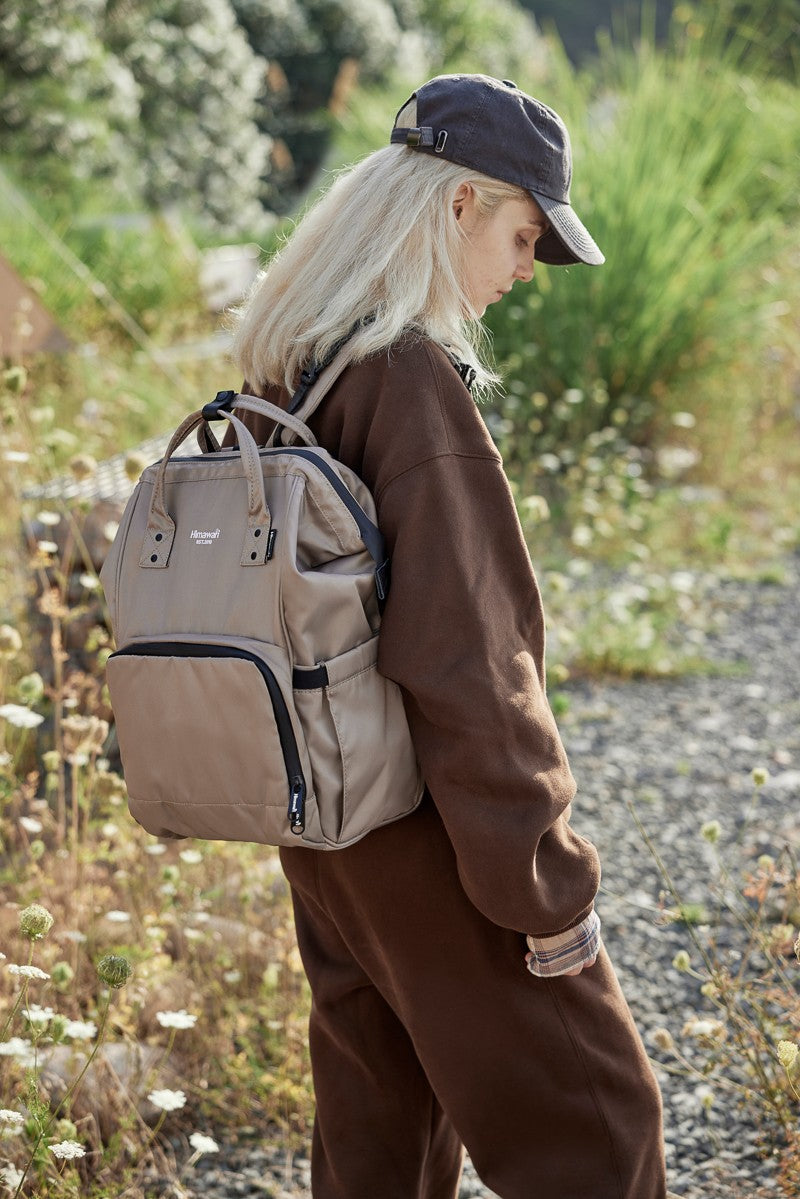 Person outdoors wearing a Himawari waterproof and anti-theft nylon backpack, showcasing its functionality and style in a natural setting.