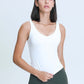 Model wearing a white Millennia V Neck Active Tank paired with dark leggings, showcasing athletic style and comfort.