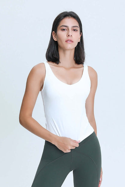 Model wearing a white Millennia V Neck Active Tank paired with dark leggings, showcasing athletic style and comfort.