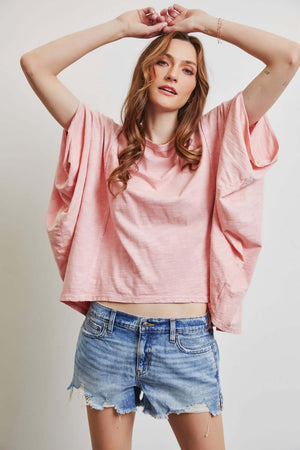 Woman wearing HEYSON Garment-Dyed Boat Neck Oversized Top in pink with denim shorts, showcasing chic and relaxed style.