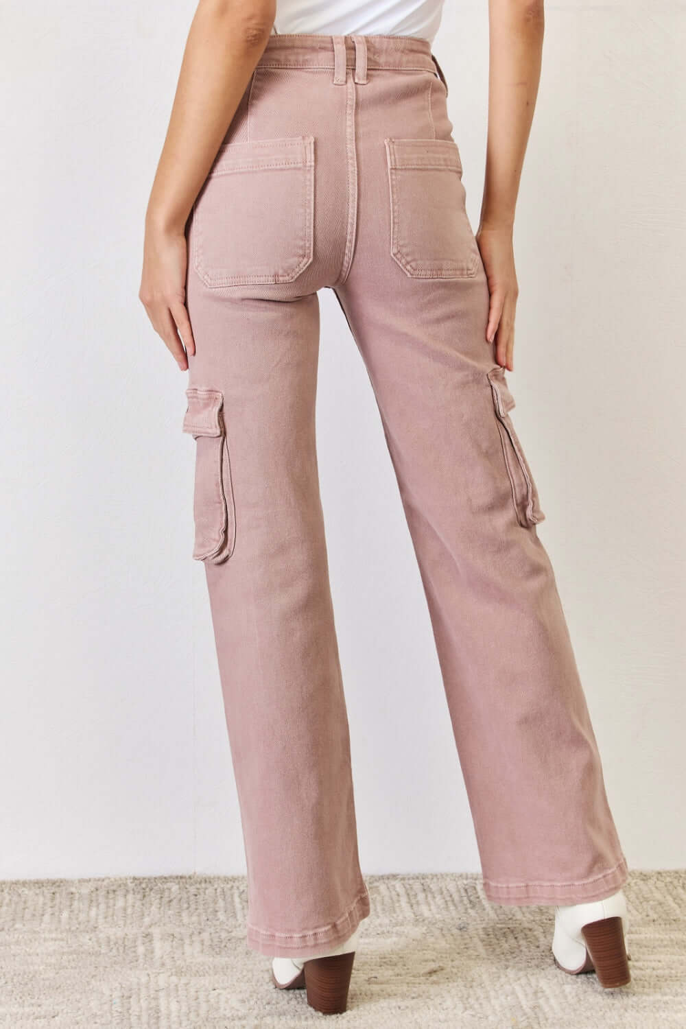 Back view of RISEN full size high-rise cargo wide leg jeans in blush pink, showing functional cargo pockets and trendy wide-leg fit.