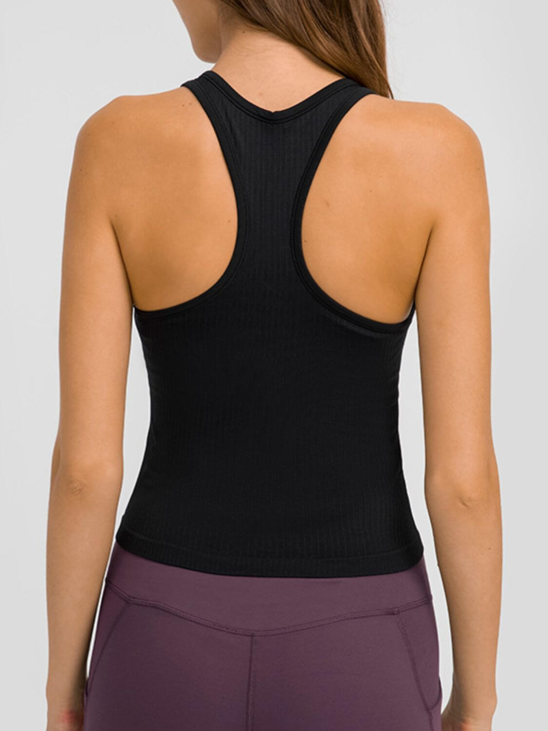 Back view of a woman wearing a black Millennia Round Neck Racerback Active Tank, showcasing comfort and sporty design.