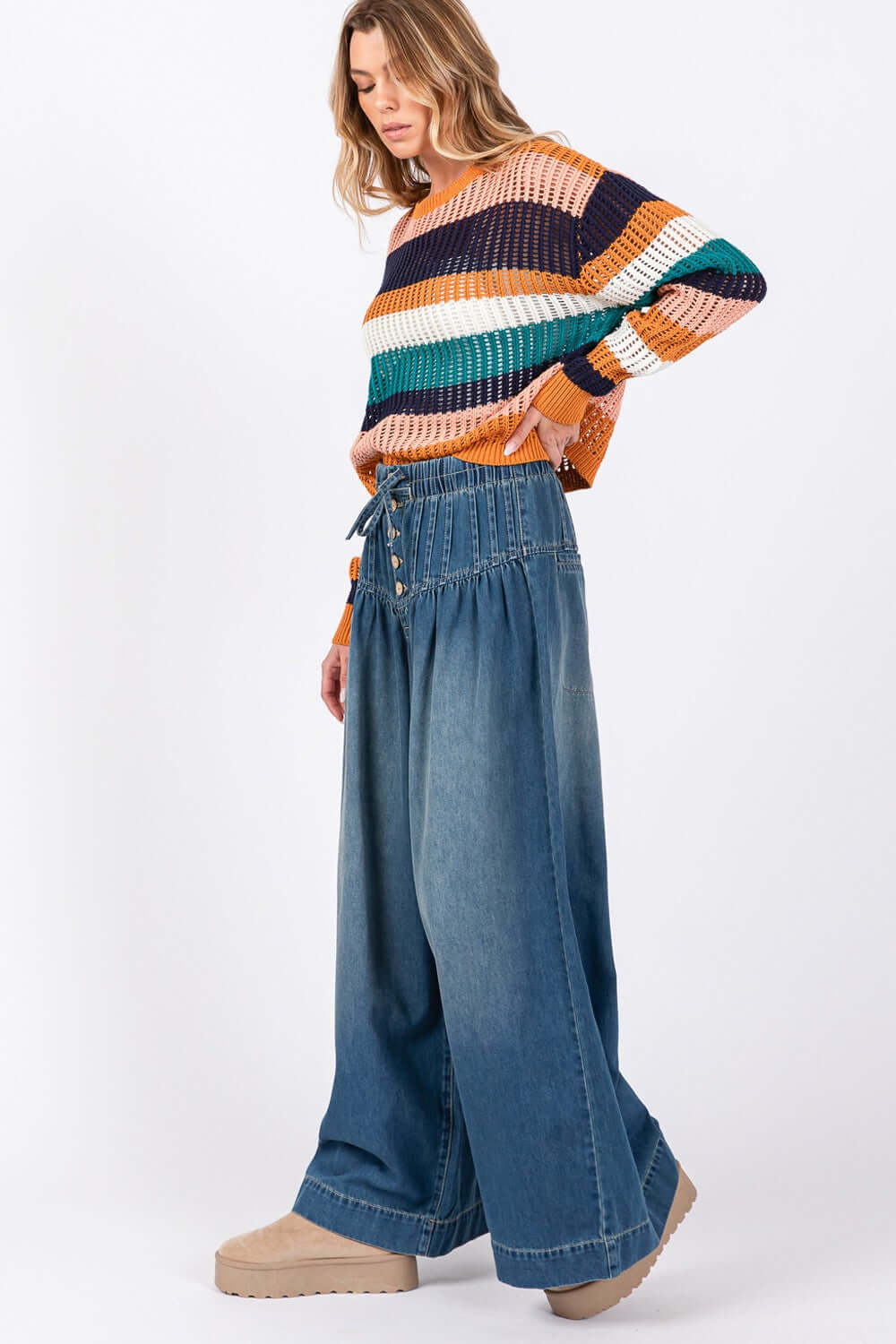 Woman wearing SAGE+FIG smocked waistband wide leg jeans for a trendy, relaxed look.