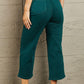 Woman wearing Judy Blue high waisted cropped wide leg jeans providing tummy control in teal, showcasing the back view.