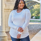 Plus-size woman wearing round neck long sleeve t-shirt paired with jeans, smiling outdoors in a casual setting.