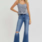 Woman wearing RISEN distressed high rise crop flare jeans with sneakers, showcasing trendy and edgy fashion style.