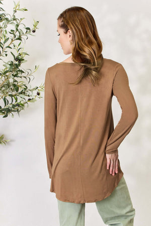 Woman wearing a luxurious brown long sleeve V-neck top made from rayon, shown from the back, paired with light green pants.