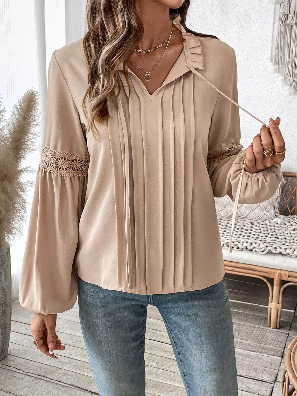 Woman wearing Perfee Frill Tie Neck Long Sleeve Blouse with lace detail, styled with blue jeans.