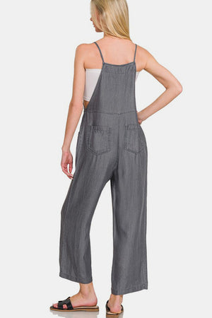 Woman wearing washed adjustable strap wide leg denim overalls, showcasing a trendy and comfortable style from the back.