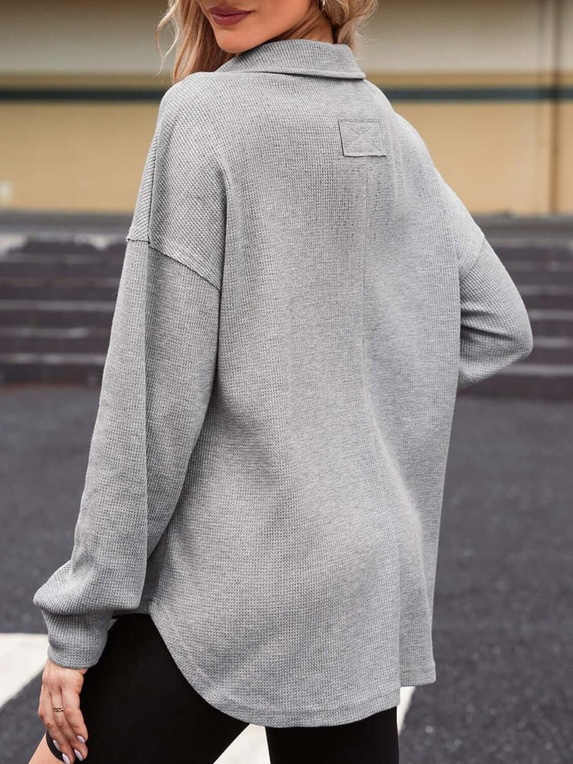 Woman wearing a grey waffle-knit Johnny collar long sleeve sweatshirt with slightly stretchy material, shown from the back.