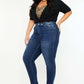 Model wearing Kancan high-rise ankle skinny jeans with double waistband in dark wash, styled with a black top and heels.