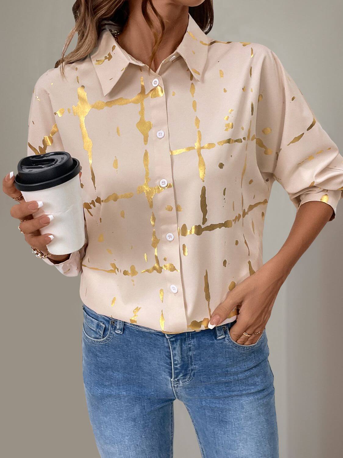 Tan long sleeve shirt with gold accents and collared neck, styled with jeans, adding elegance and comfort for any occasion.