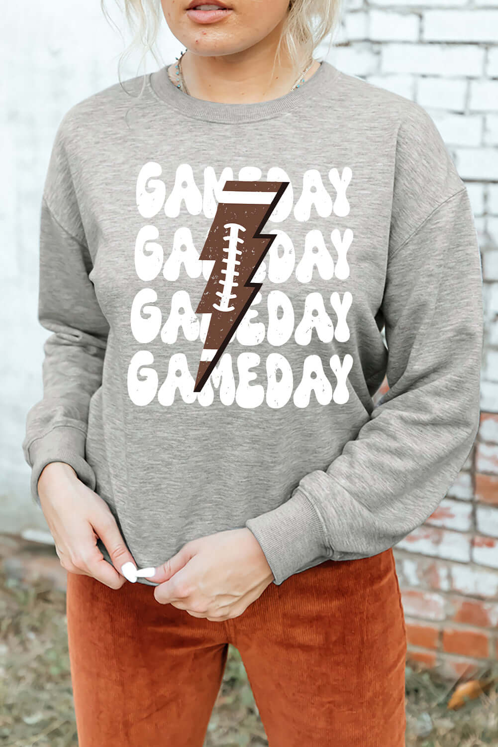 Woman wearing Bella Road Game Day Round Neck Long Sleeve Sweatshirt, showcasing game day graphic and casual style.