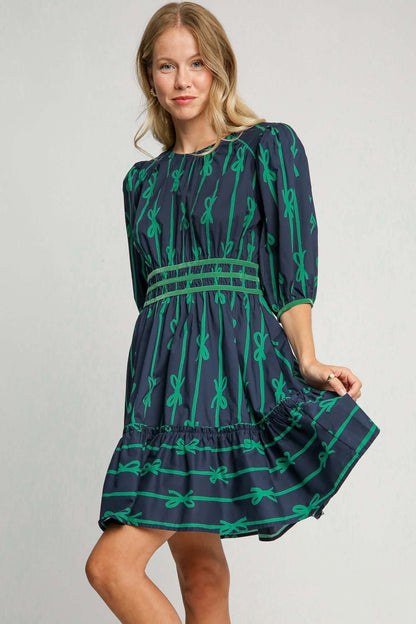 Stylish woman in a ribbon print frill contrast velvet trim half sleeve dress in navy and green, perfect for special occasions.