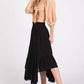 Stylish woman in a handkerchief hem black midi skirt with pockets and a beige tied blouse, showcasing a chic outfit.